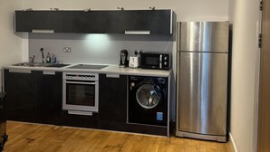 A compact kitchen with a washing machine, a refrigerator, and a microwave. - Bute Terrace Apartment - Cardiff City Center (Cardiff)