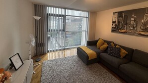 A modern living room with a grey sofa, a black and white rug, and a cityscape painting on the wall. - Bute Terrace Apartment - Cardiff City Center (Cardiff)