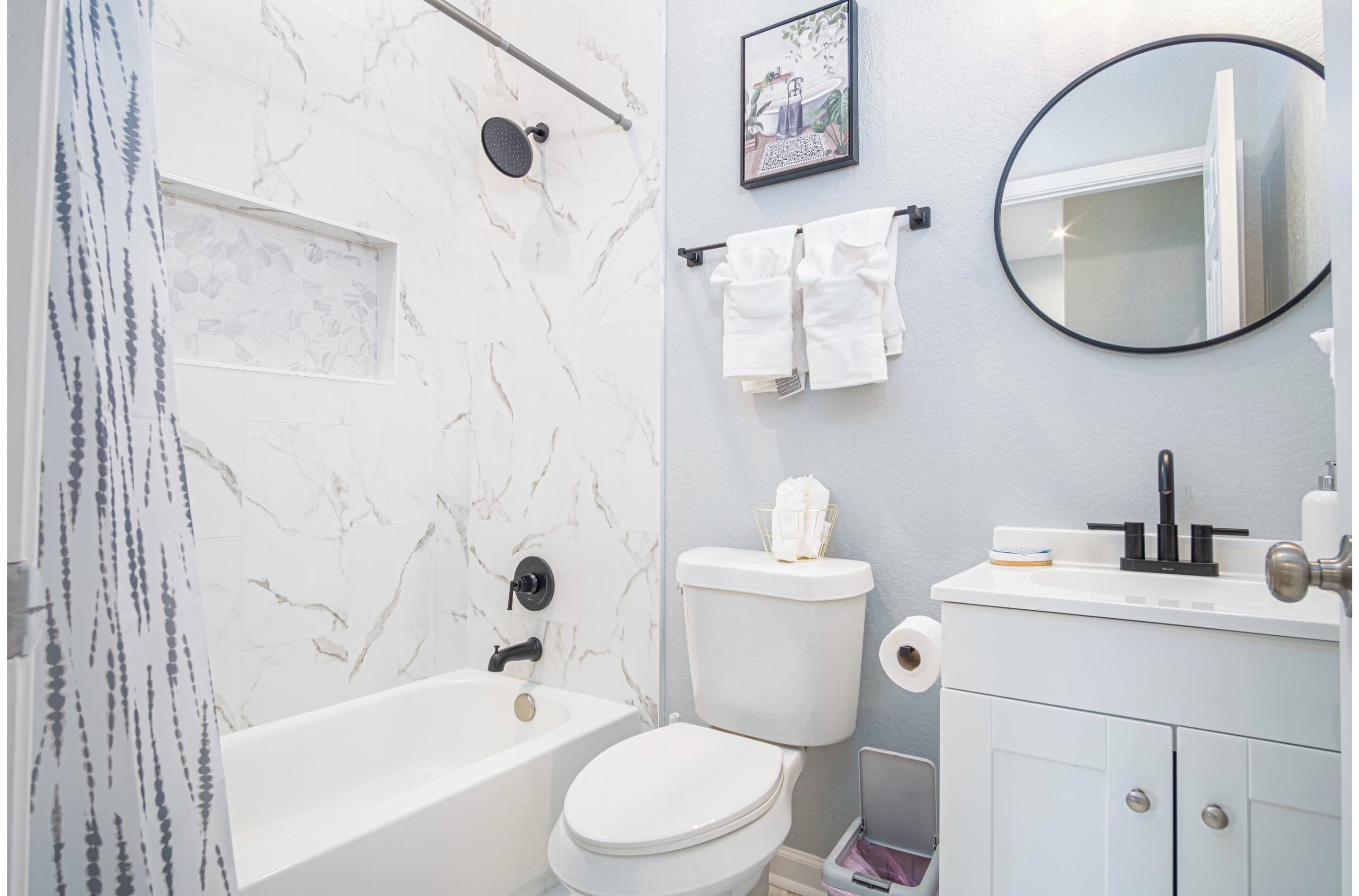 Un baño con bañera, inodoro, lavamanos y espejo.