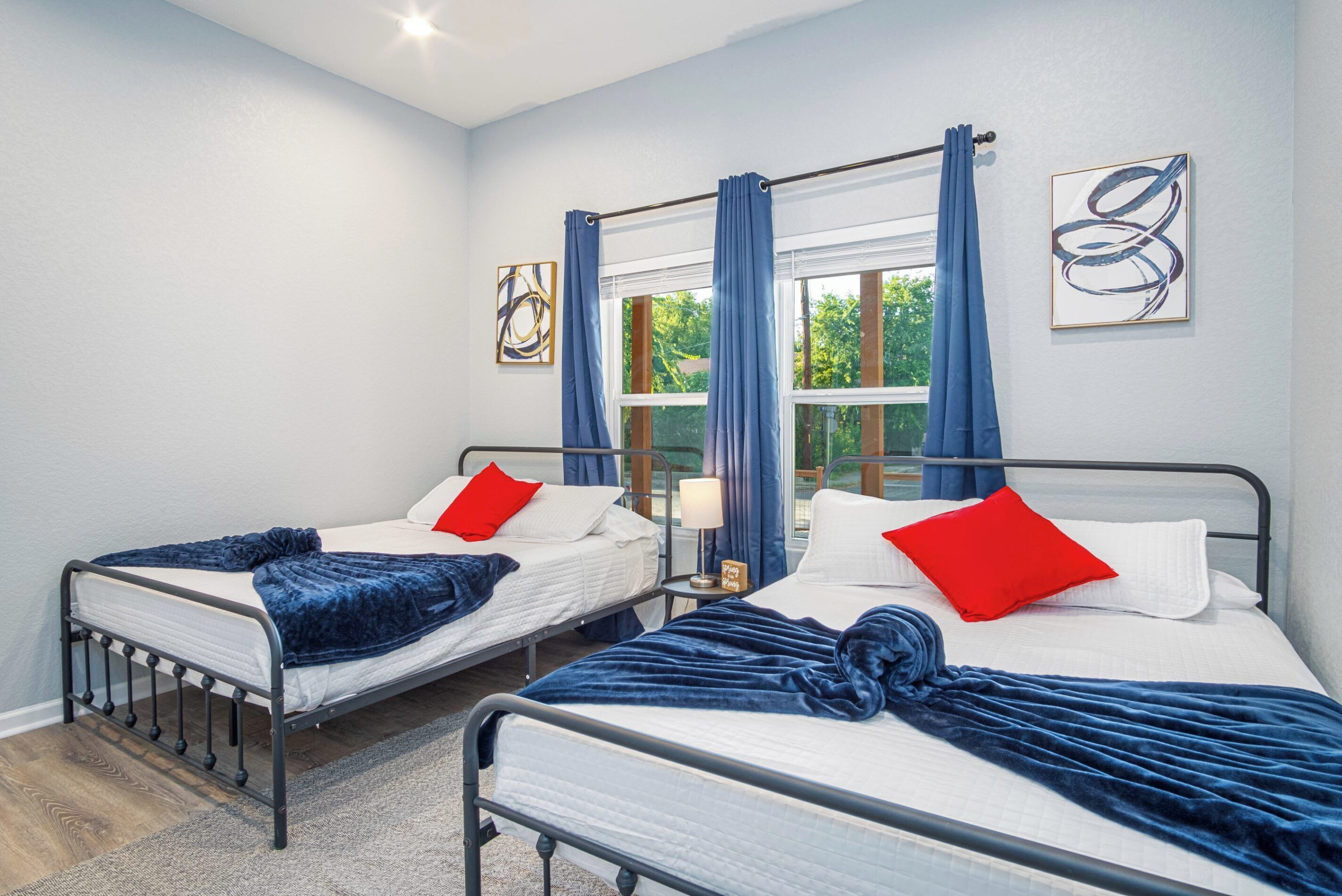 Two single beds with headboards, a window with curtains, and a wall with abstract art.