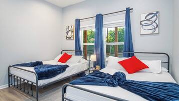 Two single beds with headboards, a window with curtains, and a wall with abstract art.
