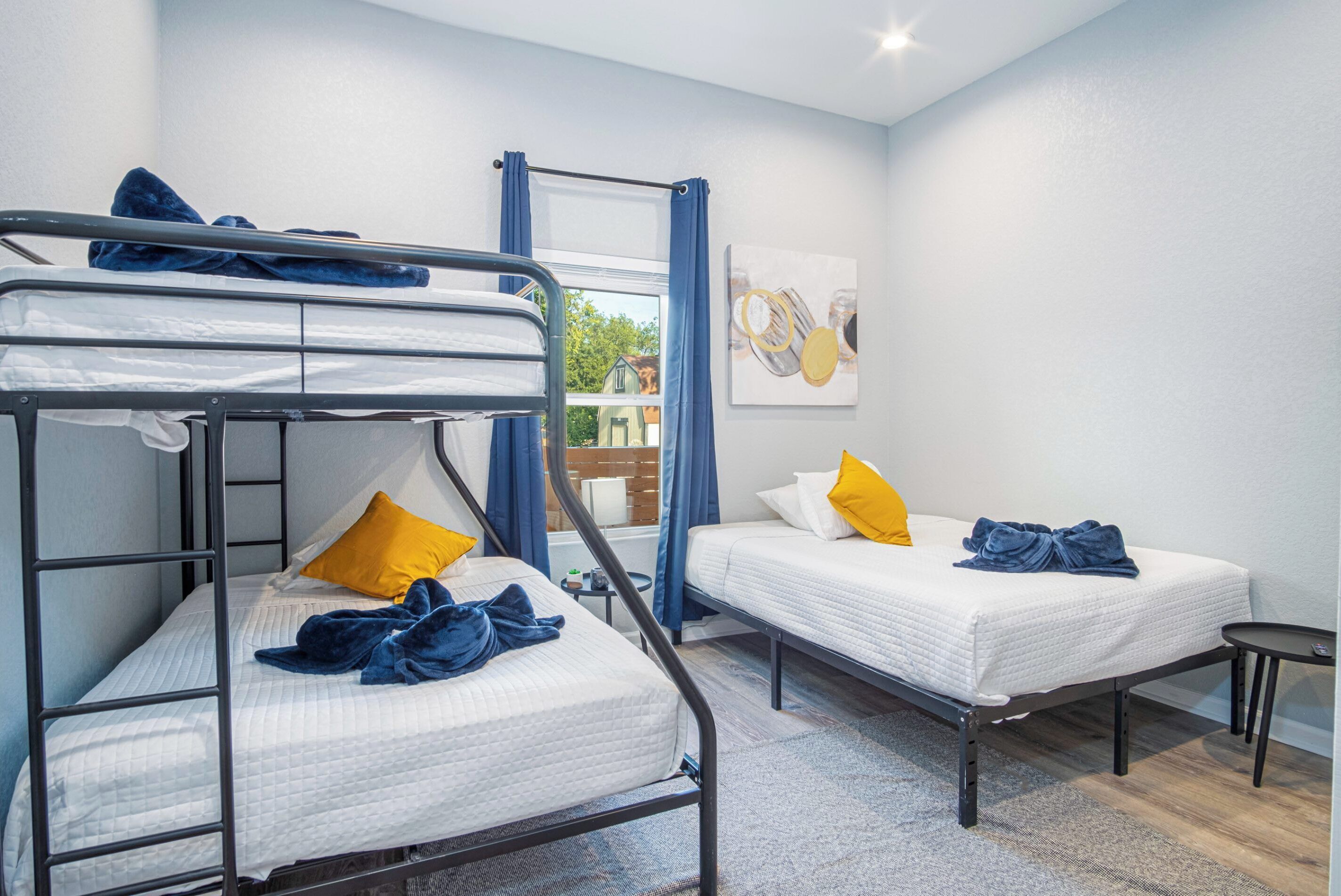 Een kamer met twee eenpersoonsbedden, een stapelbed en een kleine tafel.