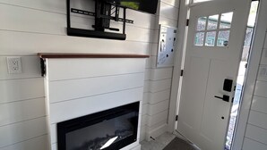Ein Zimmer mit Kamin, einem an der Wand befestigten Fernseher und einer Tür mit Fenster.