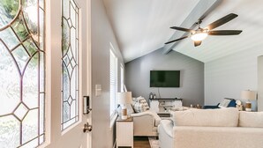 A living room with a ceiling fan, a TV mounted on the wall, and a sofa. - Historic Route 66 Hideaway (Bristow)