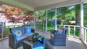 A covered porch with wicker furniture, a ceiling fan, and a view of a green yard. - Historic Route 66 Hideaway (Bristow)