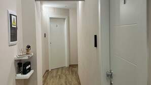 A hallway with a wooden floor, white walls, and a closed door on the right.