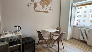 A modern room with a wooden floor, a world map on the wall, a table with chairs, a coffee machine, and a radiator.