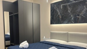 A modern hotel room with a large bed, dark blue bedding, and neatly folded towels.