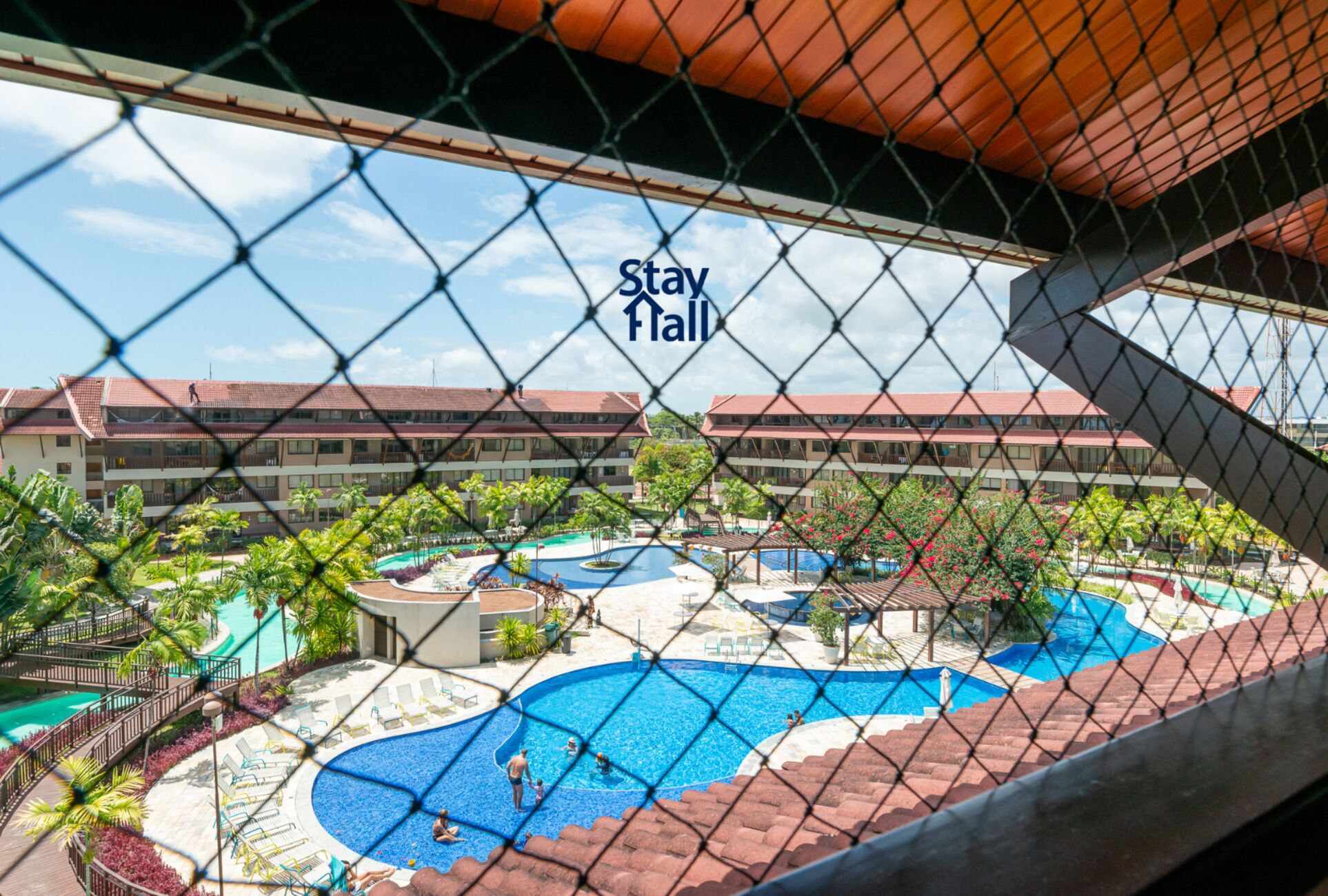 A hotel with multiple swimming pools, a 'Stay Here' sign, and a view of the resort's buildings.