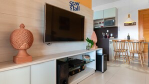 Una sala de estar moderna con un televisor de pantalla plana, una escultura decorativa y un comedor con sillas de madera y una mesa.