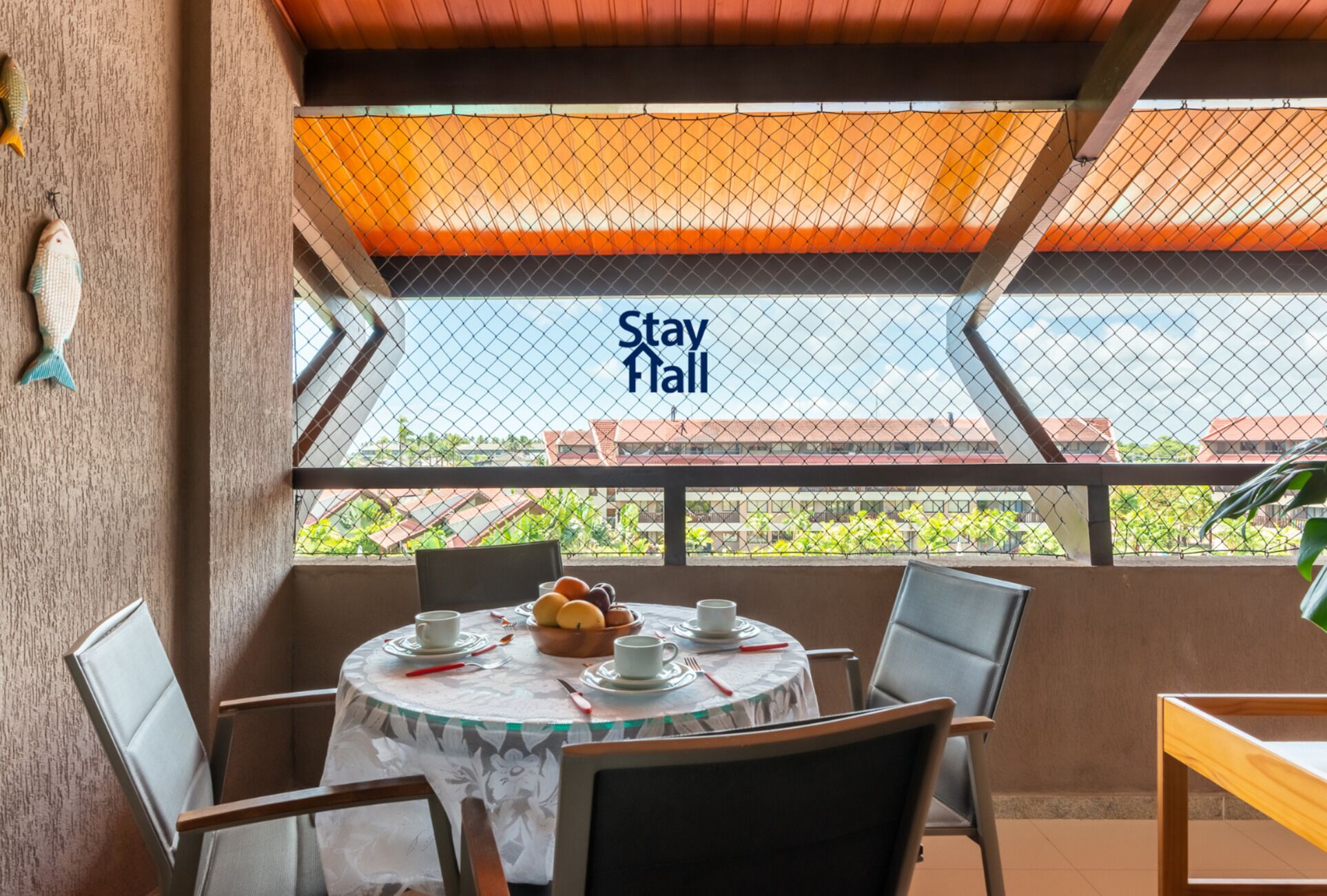 A dining area with a table set for two, chairs, and a view of a building with a 'Stay Hall' sign.