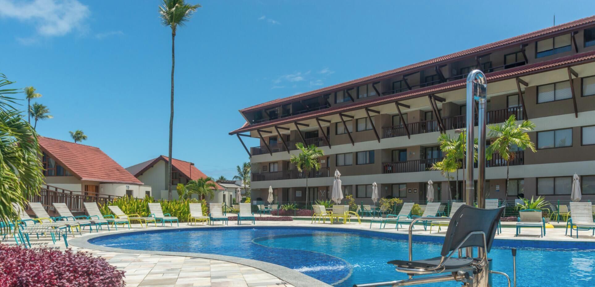 Un hôtel doté d’une piscine entourée de chaises longues et de palmiers.