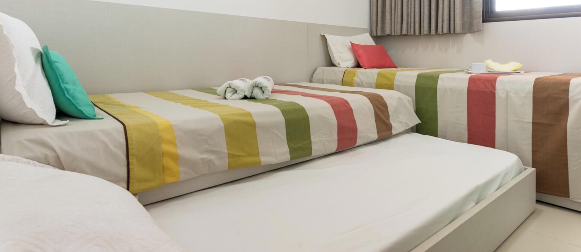 Una habitación de hotel con dos camas, cada una con ropa de cama y almohadas a rayas.