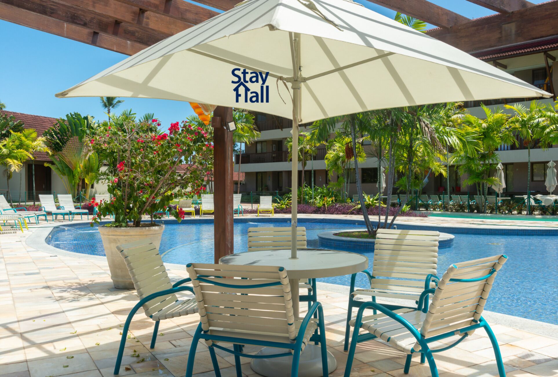 Un área junto a la piscina con un letrero que dice 'Stay Hall', sillas de descanso y una piscina.