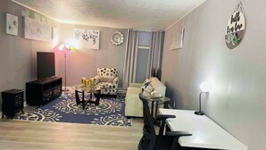 Una sala de estar con televisor, mesa de centro, sofá y una mesa de comedor con sillas.
