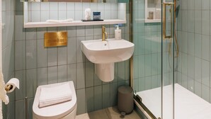 A modern bathroom with a glass shower enclosure, a white sink, and a toilet. - Modern Studio Flat in North London (London)