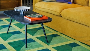A modern living room with a yellow sofa, a black coffee table, and a large plant. - Modern Studio Flat in North London (London)