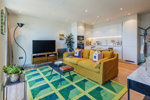 A modern living room with a sofa, coffee table, and a flat-screen TV. - Modern Studio Flat in North London (London)