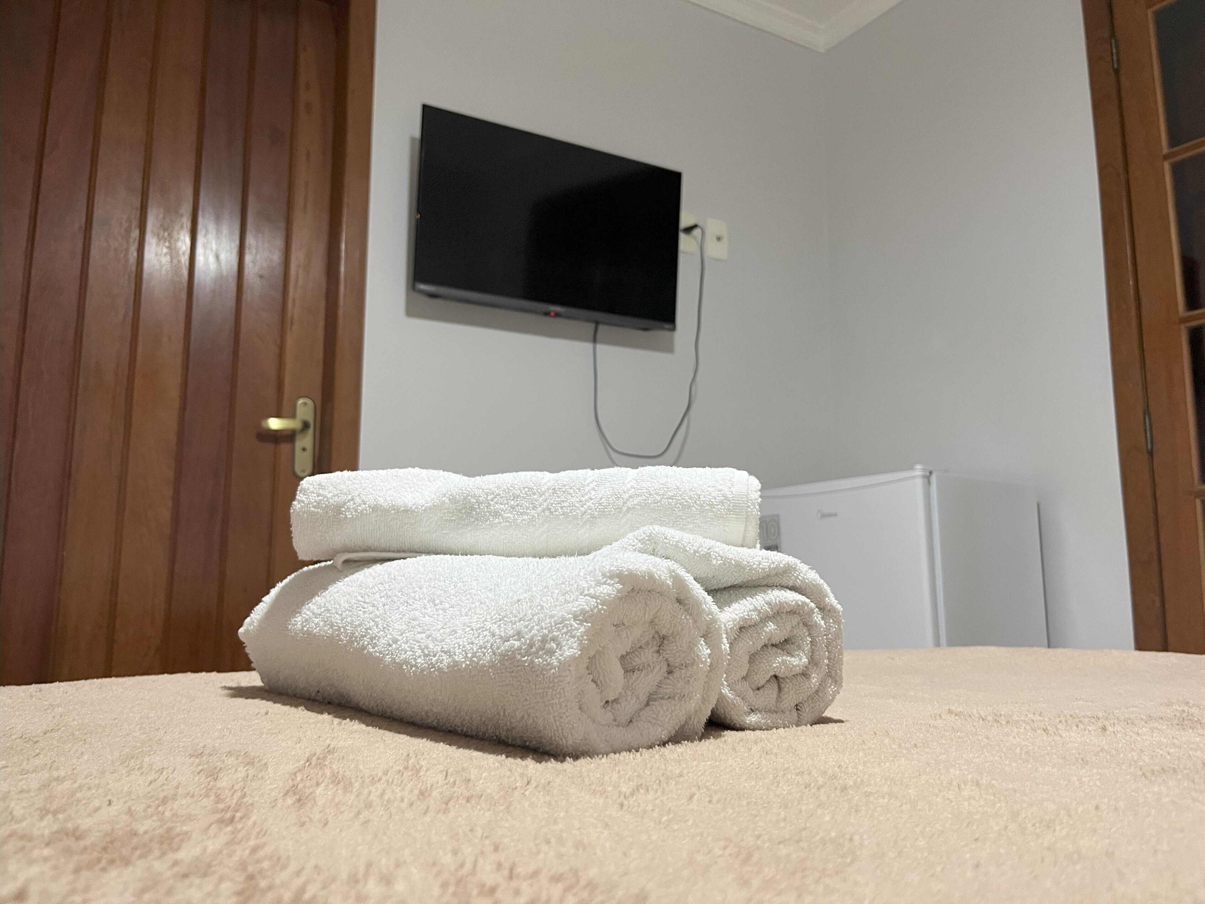 Una habitación con puerta de madera, pared blanca y radiador blanco.