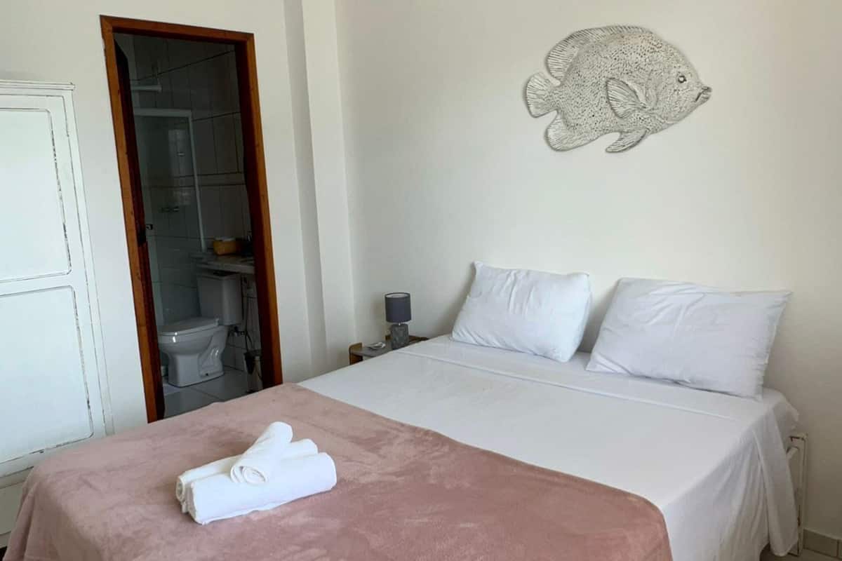 Une chambre à coucher avec un lit, une serviette, une table de chevet, une lampe et une décoration murale représentant des poissons.