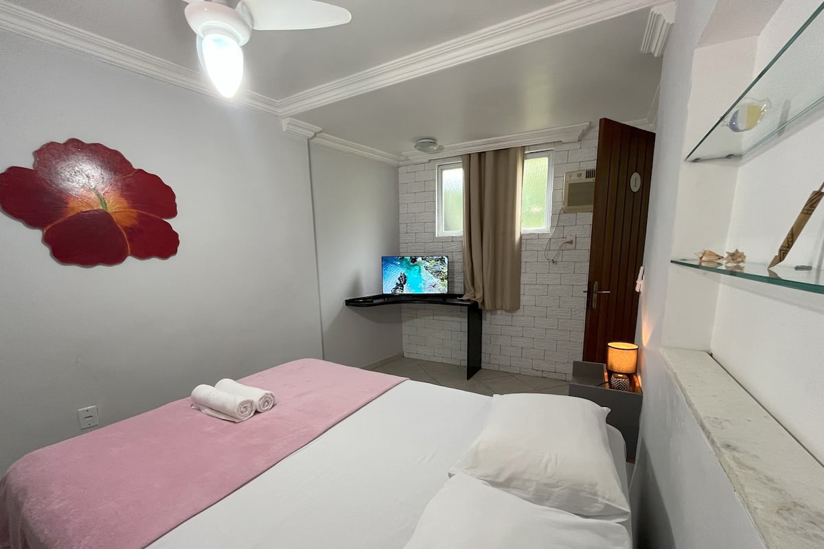 Une chambre d’hôtel avec un lit, une télévision, un petit bureau et une salle de bain.