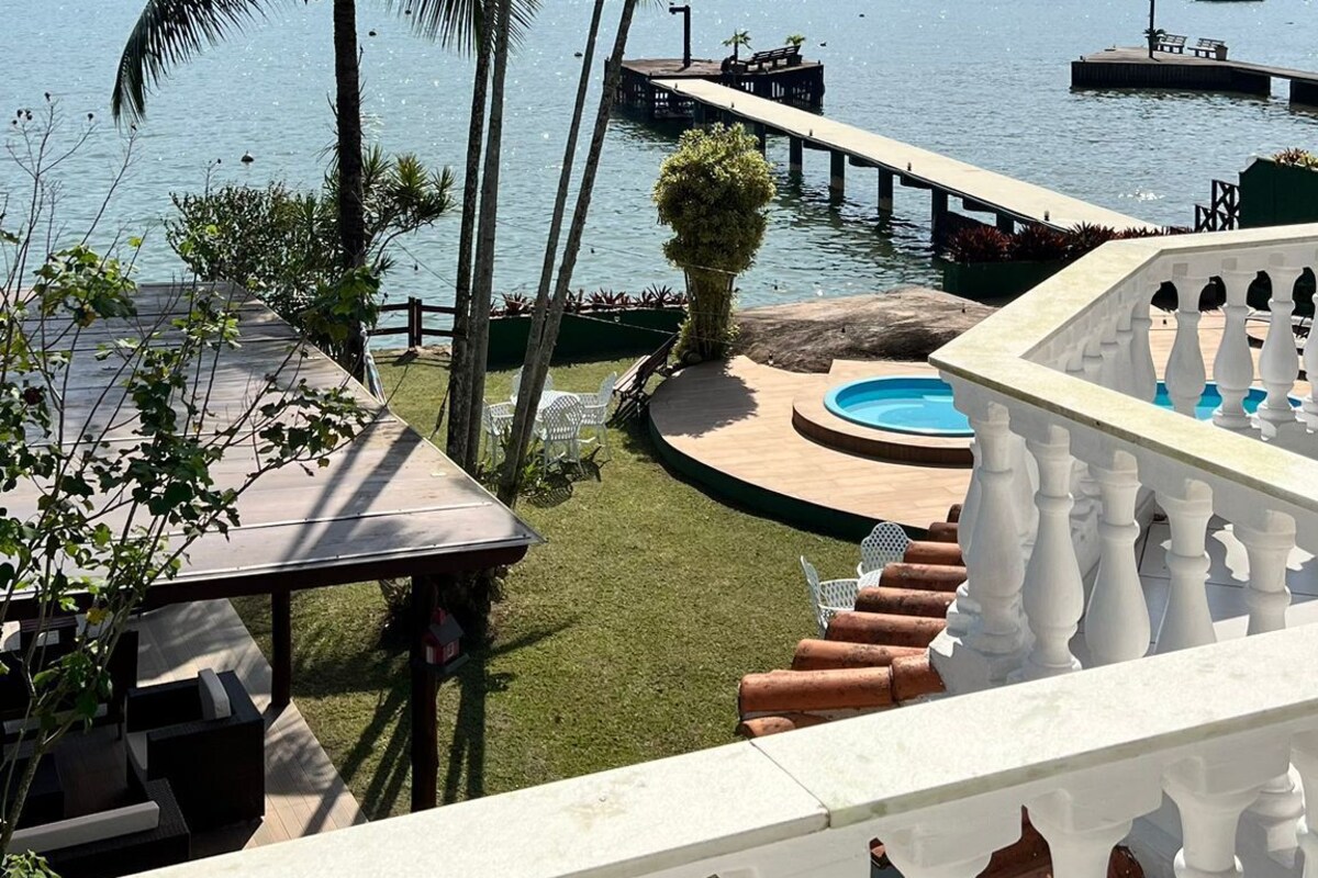 A view from a balcony overlooking a pool, palm trees, and a marina with boats.