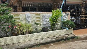 A residential house with a tiled roof, a stone wall, and a gated entrance. - Room in Guest Room - Stunning Home Great Location (Pattaya)