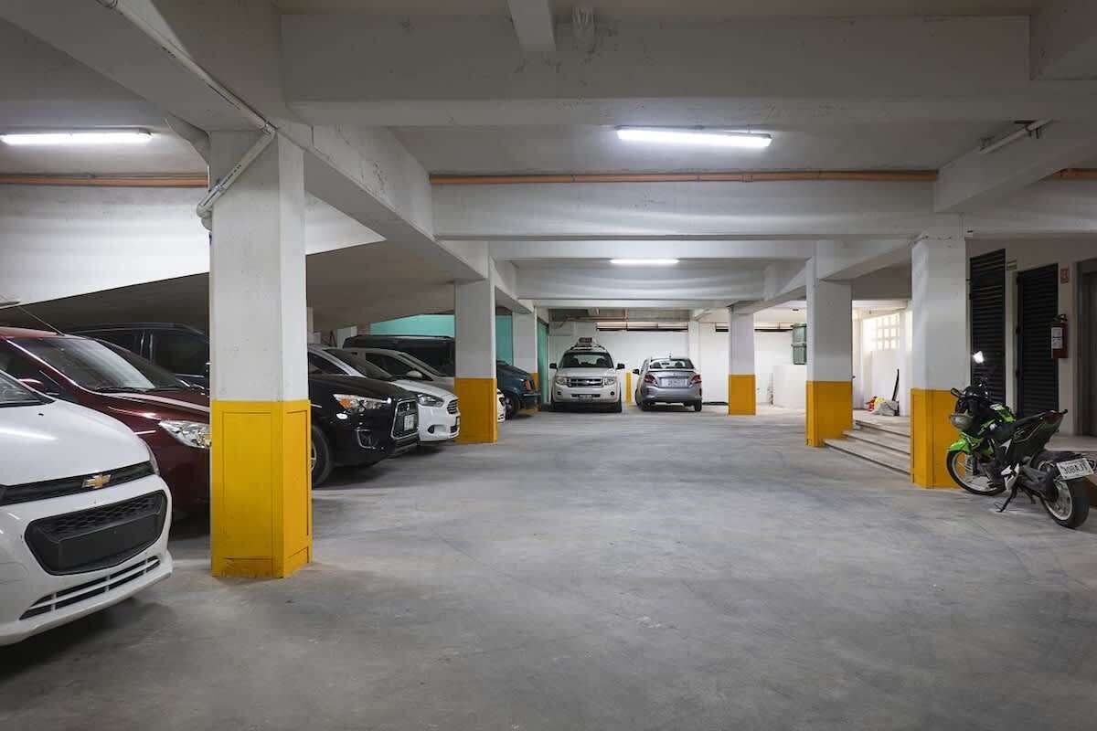 A multi-level parking garage with several cars and a motorcycle parked.