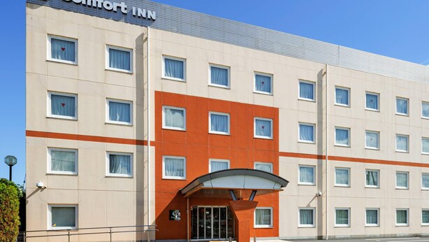 Ένα ξενοδοχείο Comfort Inn με μια μοντέρνα πρόσοψη, πολλά παράθυρα και έναν καθαρό ουρανό.