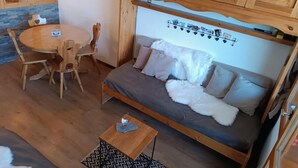 Ett mysigt rum med en soffa i trä, ett runt träbord och tillhörande stolar.