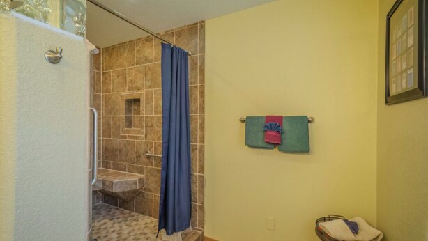 A bathroom with a shower, a sink, and a towel rack with towels. - Byrd Mountain - Upper Canyon Gem - Large Game Room (Ruidoso)