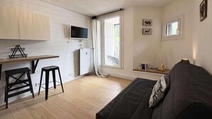 Een knus woongedeelte met een kitchenette, een bank en een eethoek.