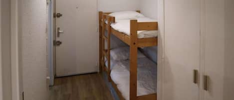 Un pasillo estrecho con una litera de madera y una puerta.