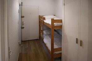A narrow hallway with a wooden bunk bed and a door.