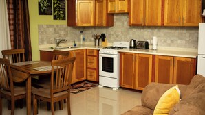 A kitchen with wooden cabinets, a stove, a sink, and a dining area with chairs. - Modern Comfort: Private 1BR In Basseterre (Basseterre)