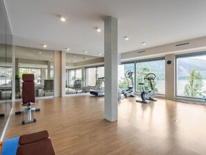 A spacious gym with exercise equipment, large windows, and a view of a lake.
