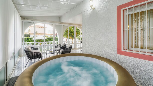 A hot tub area with a view of a building and greenery outside.