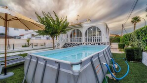 An outdoor swimming pool with a white house in the background.