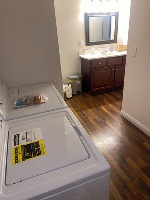 A laundry room with stacked washers and dryers, a trash can, and a wooden floor. - Cozy building in charming Loretto with WiFi, AC (Loretto)
