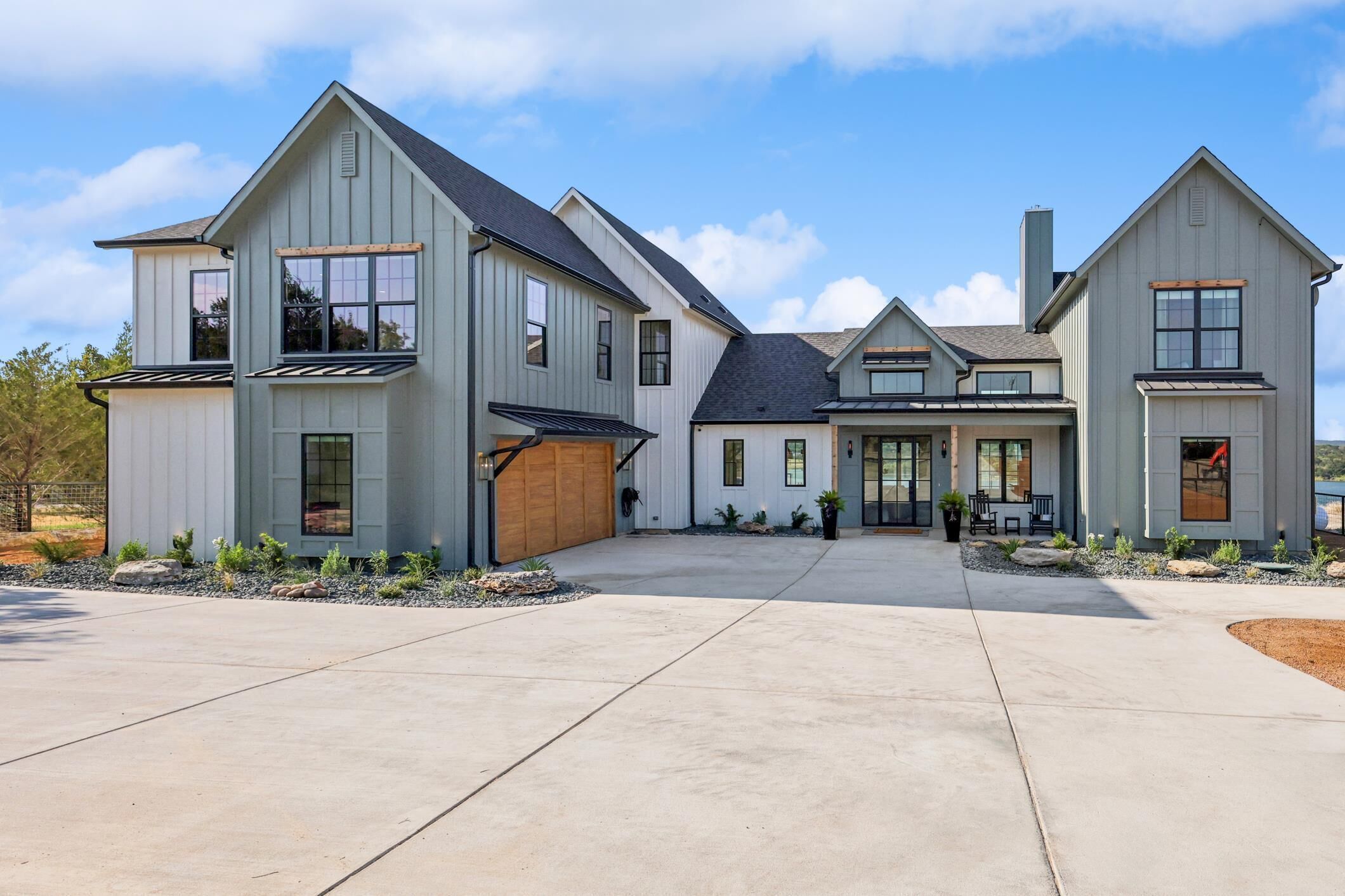A modern two-story house with a large driveway and a covered patio area.