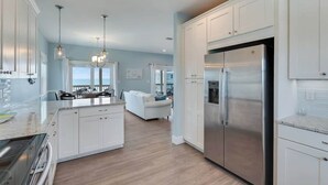 A modern kitchen with white cabinetry, stainless steel appliances, and a central island. - Cape Ocean Front~Jacuzzi~Elevator~Arcade Games! (Port St. Joe)