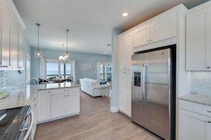 A modern kitchen with white cabinetry, stainless steel appliances, and a central island. - Cape Ocean Front~Jacuzzi~Elevator~Arcade Games! (Port St. Joe)