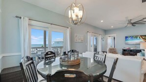 A modern dining area with a glass table, dark chairs, and a decorative centerpiece. - Cape Ocean Front~Jacuzzi~Elevator~Arcade Games! (Port St. Joe)