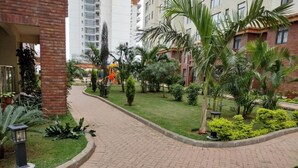 A paved pathway with a brick pattern, surrounded by well-maintained grass and various shrubs. - Lenayan Park View Deluxe Double Room (Nairobi)