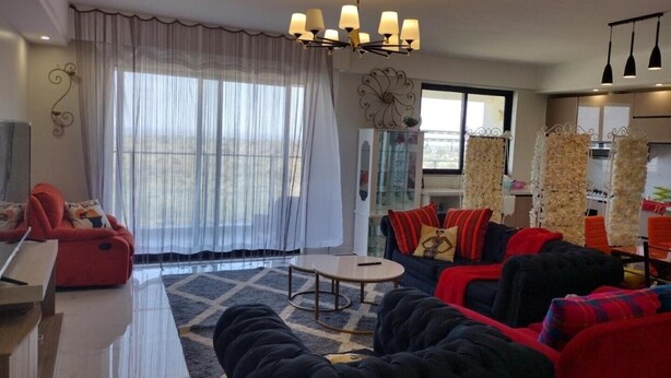 A modern living room with a sofa set, a coffee table, and a chandelier. - Lenayan Park View Deluxe Double Room (Nairobi)