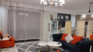 A modern living room with a sofa, two coffee tables, and a decorative rug. - Lenayan Park View Deluxe Double Room (Nairobi)