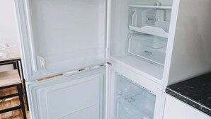 Un refrigerador abierto con varios compartimentos, incluyendo un congelador y un cajón.