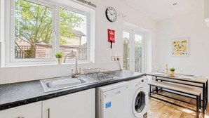 Una cocina moderna con lavadora integrada, un lavamanos y una zona de comedor con banco.
