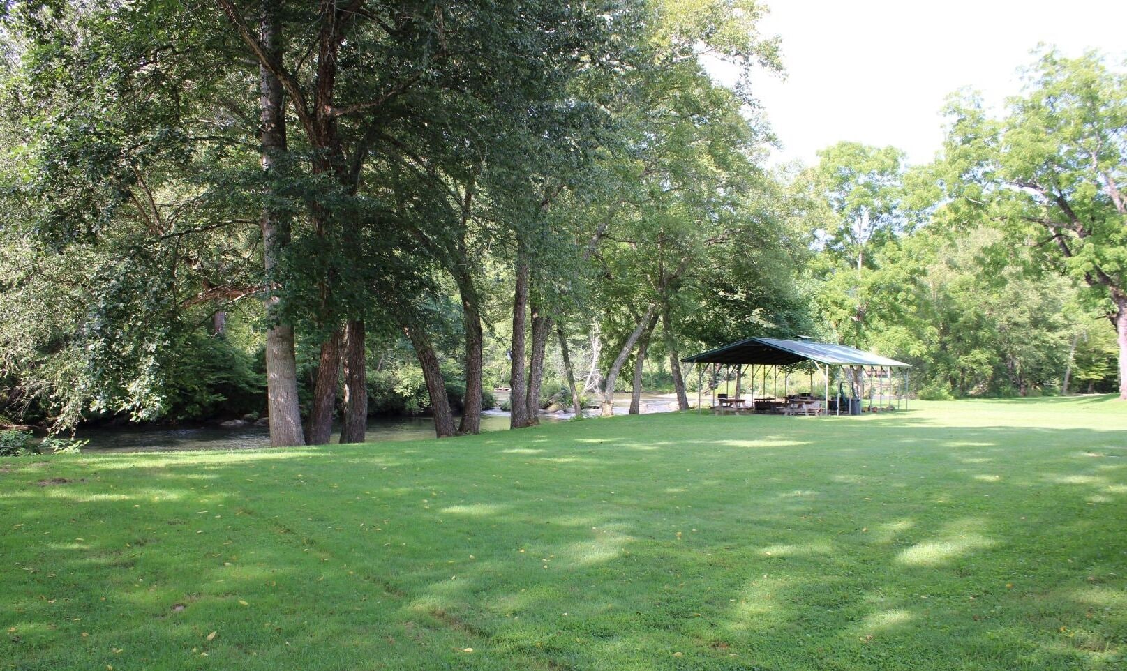 A grassy park area with a covered pavilion and picnic tables.