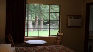 A room with a large window, a bed, a chair, and an air conditioning unit. - Two Rivers Lodge (Bryson City)